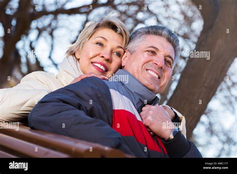 Positive Mature Husband And Wife Hugging Each Other Sitting On Park Bench Stock Photo Alamy