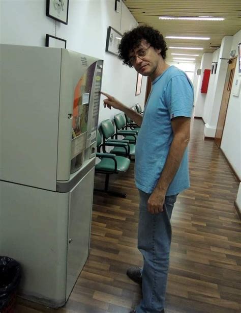 A Man Standing Next To A Refrigerator In A Room