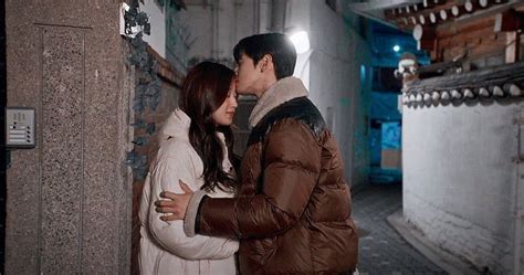 A Man And Woman Standing Next To Each Other In Front Of A Building At Night