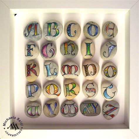 Colorful Lombardic Capitals Written On Pebbles By Michaela Seidl