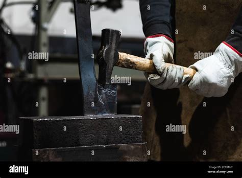 Crop Anonymous Craftsmen In Gloves Making Hot Metal Detail With Hammer In Blacksmith Workshop
