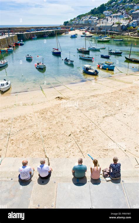 Visitors Tourists Relaxing In The Sun On The Harbour Wall In The