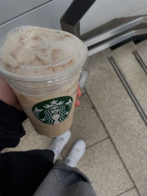 A Person Holding Up A Starbucks Drink In Their Hand