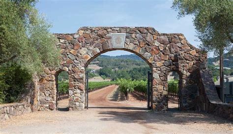 A Stone Arch With A Basketball Hoop On It In The Middle Of A Dirt Road