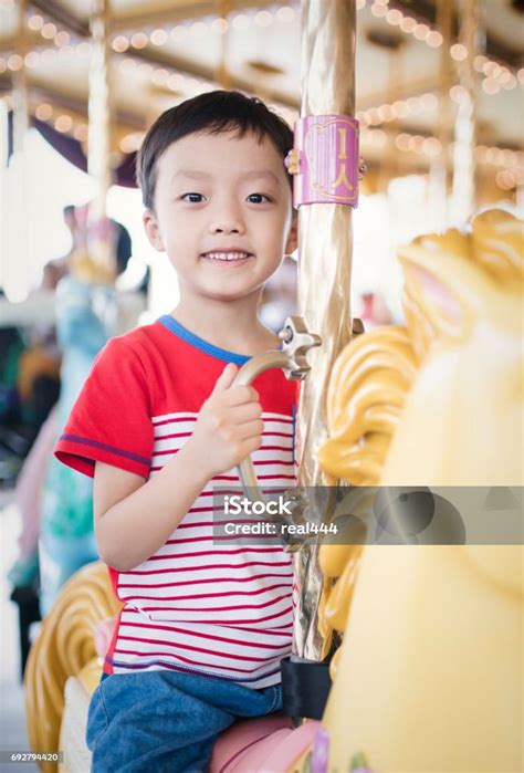 Child Having Fun Riding On A Colorful Carnival Carousel Stock Photo