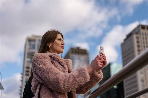 Woman Uses Her Smartphone To Take Pictures In The City By Stocksy