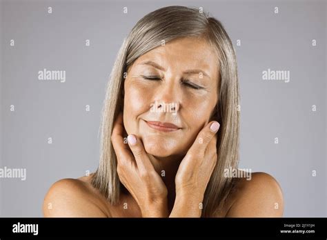 Stunning Mature Woman Touching Her Smooth Healthy Skin On Face And Keeping Eyes Closed While