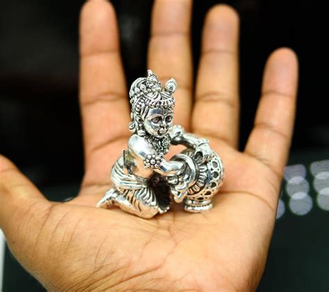 a small silver figurine sitting on top of someone's hand