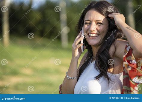 Woman Laughing While Talking On Phone Outdoors On A Sunny Day Stock