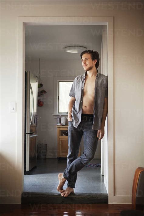 Full Length Of Man Leaning On Doorway At Home Stock Photo