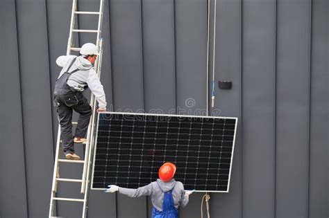 Workers Lifting Up Photovoltaic Solar Module While Installing Solar