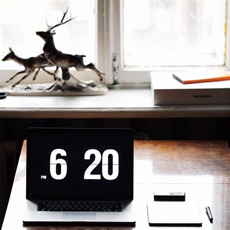 a laptop computer sitting on top of a wooden desk next to a statue of a ...