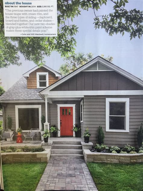 A Gray House With Red Front Door And Brick Walkway Leading Up To The