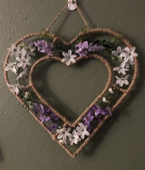 A Heart Shaped Hanging On The Wall With Purple And White Flowers In It