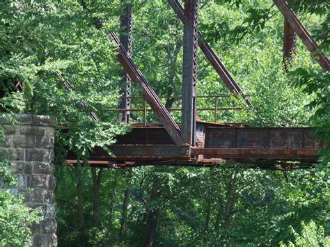 An Old Rusted Bridge In The Middle Of Some Trees