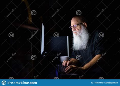 Mature Bald Bearded Man Working Overtime At Home In The Dark Stock