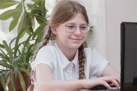 Premium Photo Smart Schoolgirl Does Homework Sitting At Her Desk Writes With A Pen In Her