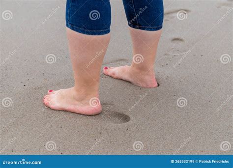 Pierna De Las Mujeres Con Pantalones Jalados Con Los Pies En El Mar Y