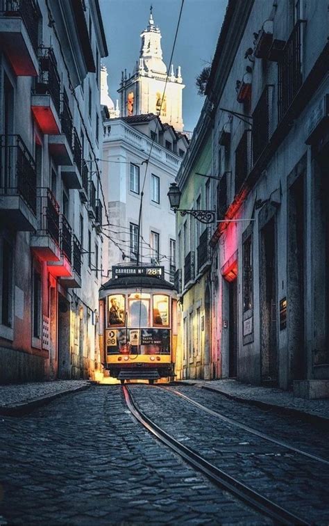 A Trolley Car Traveling Down A Street Next To Tall Buildings At Night