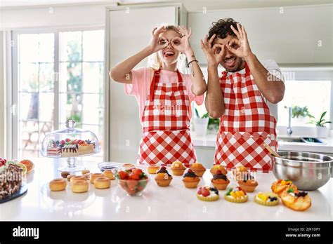 Couple Of Wife And Husband Cooking Pastries At The Kitchen Doing Ok Gesture Like Binoculars