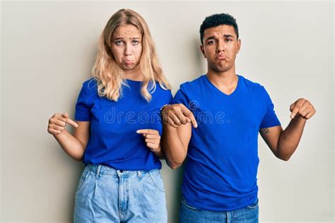 Young Interracial Couple Wearing Casual Clothes Pointing Down Looking