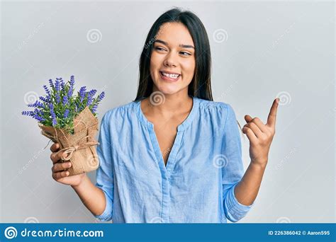 Young Hispanic Girl Holding Lavender Plant Smiling Happy Pointing With