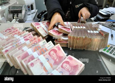 A Chinese Clerk Counts RMB Renminbi Yuan Banknotes At A Bank In