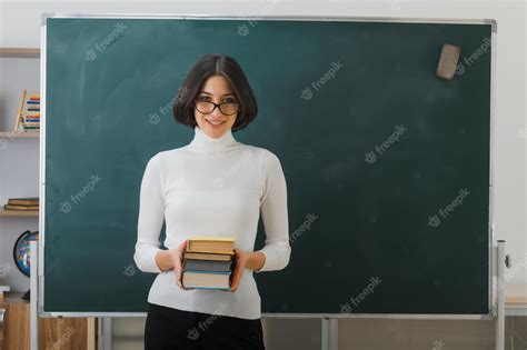 Premium Photo Smiling Young Female Teacher Wearing Glasses Holding