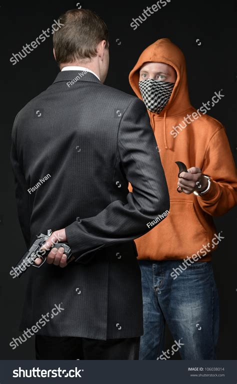 Man In Suit Holding Gun Behind His Back In Front Of Him Man With Knife