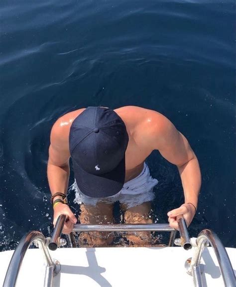 A Man Standing On Top Of A Boat In The Water With His Hat Over His Head