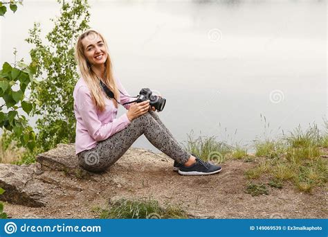 Fot Grafo De La Mujer Joven Que Se Sienta En El Lago En Verano Imagen