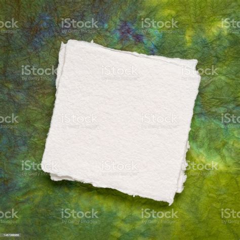 Small Square Sheet Of Blank White Paper Against Colorful Marbled Paper