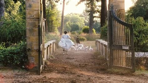 A Man Walking Down A Dirt Road Next To A Gate