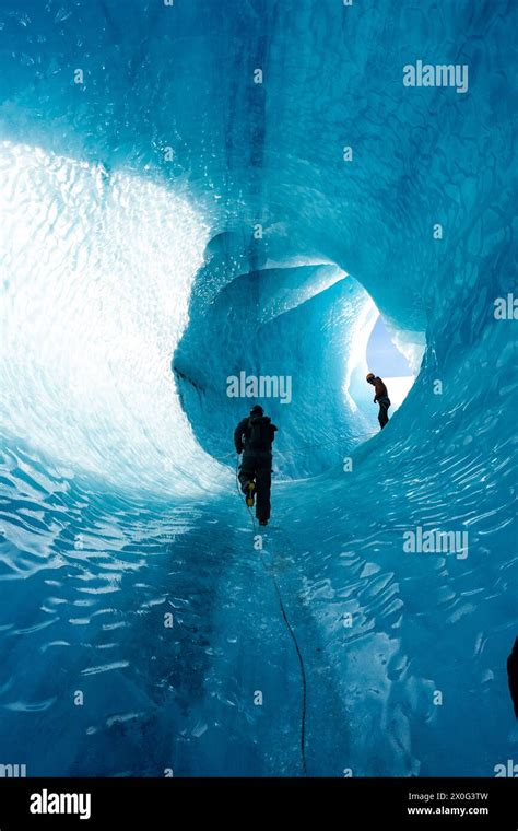 Man Climbing Up Glacier Cave In Iceland Winter Gear Blue Iceberg