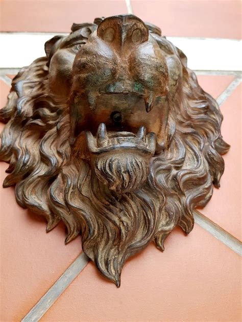 A Statue Of A Lion Head On A Tile Floor In Front Of A Red Wall