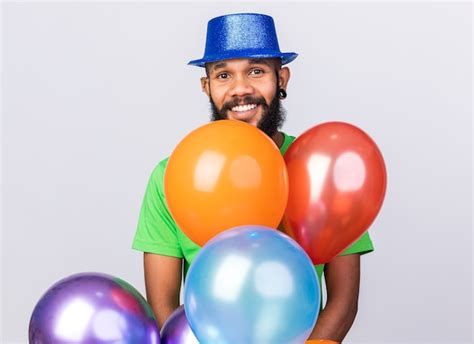 Sonriente joven afroamericano vistiendo gorro de fiesta de pie detrás