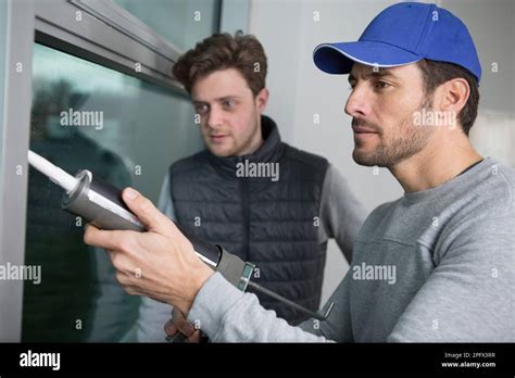 Apprentice Being Shown How To Apply Caulk To Window Stock Photo Alamy