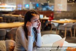 Contemplative Brunette Woman In A Restaurant Working On Her Laptop With