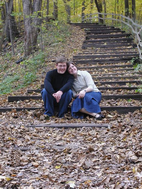 Two People Sitting On Steps In The Woods With Leaves All Over Them And