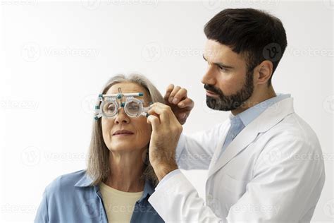 Optometrist examining senior woman's vision with phoropter during eye