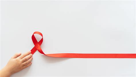 흰색 배경에 어린이 손에 있는 Aid 빨간 리본 Hiv Aids 및 암에 대한 투쟁의 상징 도움이 필요한 사람들을 돕는 개념