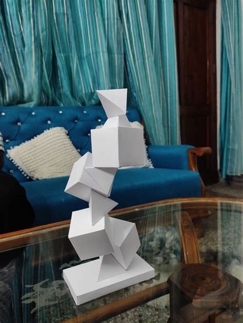 A White Sculpture Sitting On Top Of A Glass Table In Front Of A Blue Couch