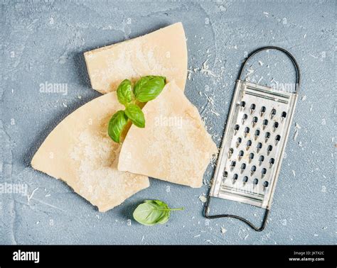 Los Trozos De Queso Parmesano Con Rallador De Metal Y Albahaca Fresca