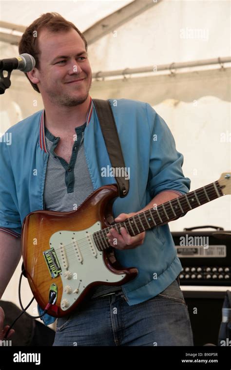 A Band Member Smiles As He Plays Electric Guitar In A Marquis Stock