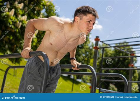 Athletic Caucasian Shirtless Man Practicing Dips On Parallel Bars Training Triceps On Playground