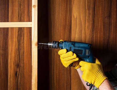 Woodworker Drills A Hole With An Electric Drill In A Wood Board Close