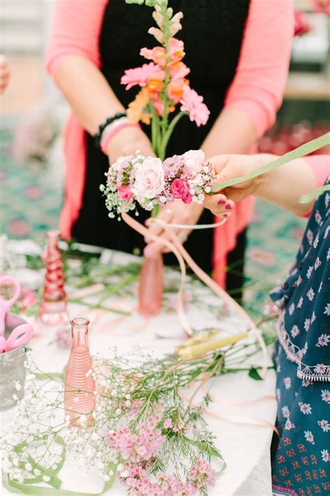 Two Women Are Arranging Flowers In Vases On A Table With Pink And Green