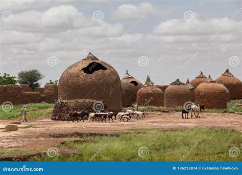 Farmer In Western Africa Landscape With Traditional African Mud Huts