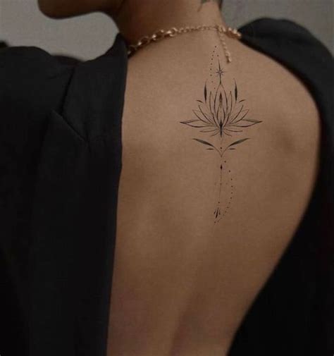 The Back Of A Woman S Neck With A Flower Tattoo On It