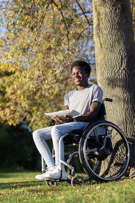 Smiling Black Guy In Wheelchair Enjoying Lunch In City Park Stock Photo